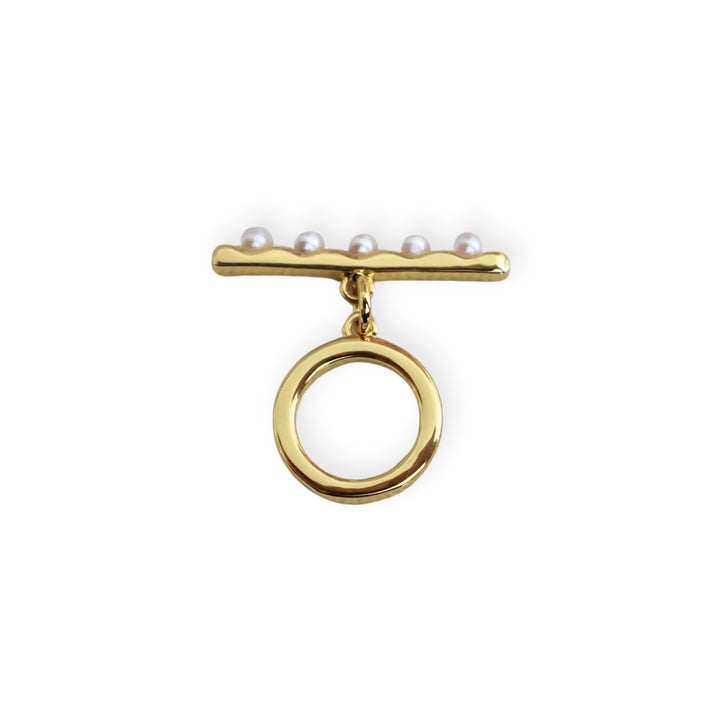Broche tipo T de chapa de oro con perla sintética sobre fondo blanco