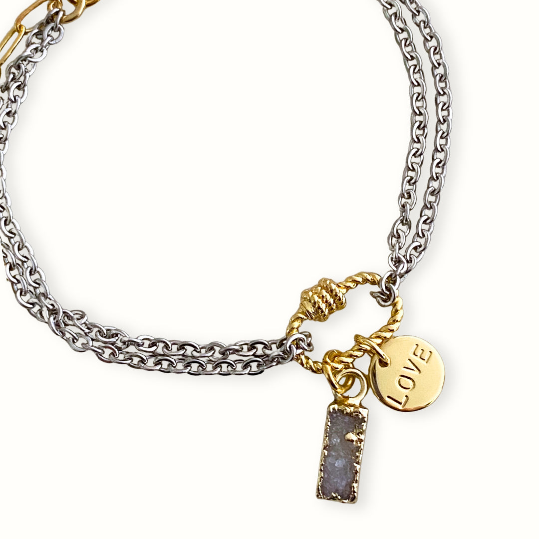 Brazalete plateado con cadena de acero inoxidable, conector central de chapa de oro, dije Love y druzy biselado. 