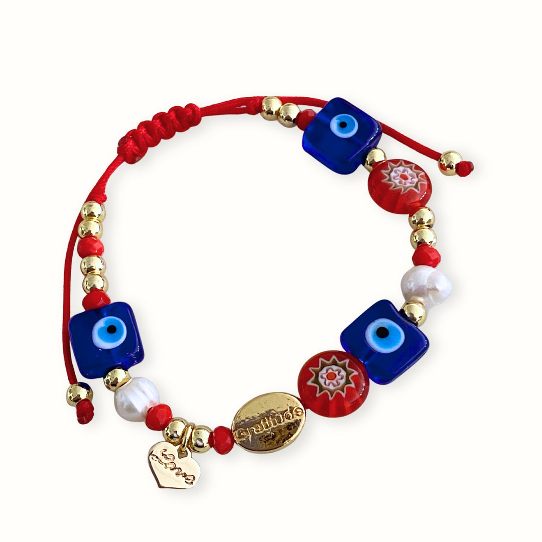Pulsera tejida ajustable con dije Love de chapa de oro, ojo turco de murano, perla de río y murano millefiori. 