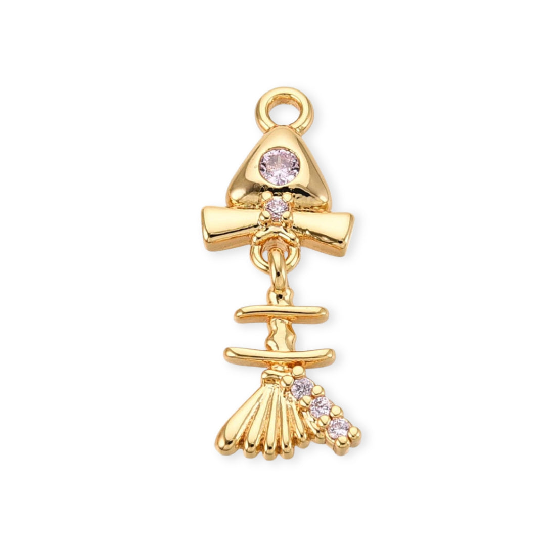 Dije de pescado de chapa de oro con zirconia rosa en el ojo y aleta móvil sobre fondo blanco