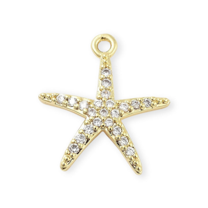 Dije estrella de mar en chapa de oro con zirconias alrededor sobre fondo blanco