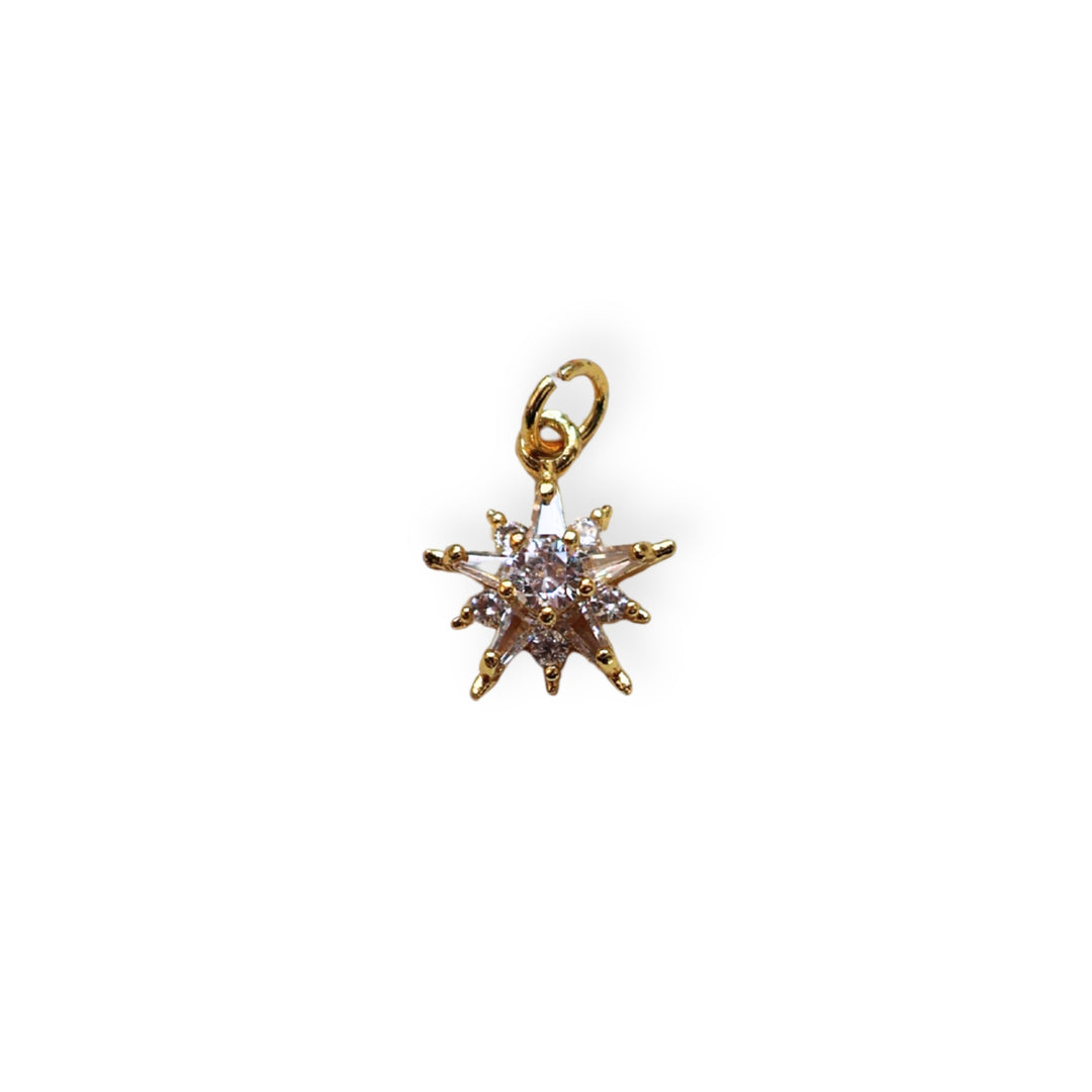Dije estrella dorado con zirconia en el centro sobre fondo blanco