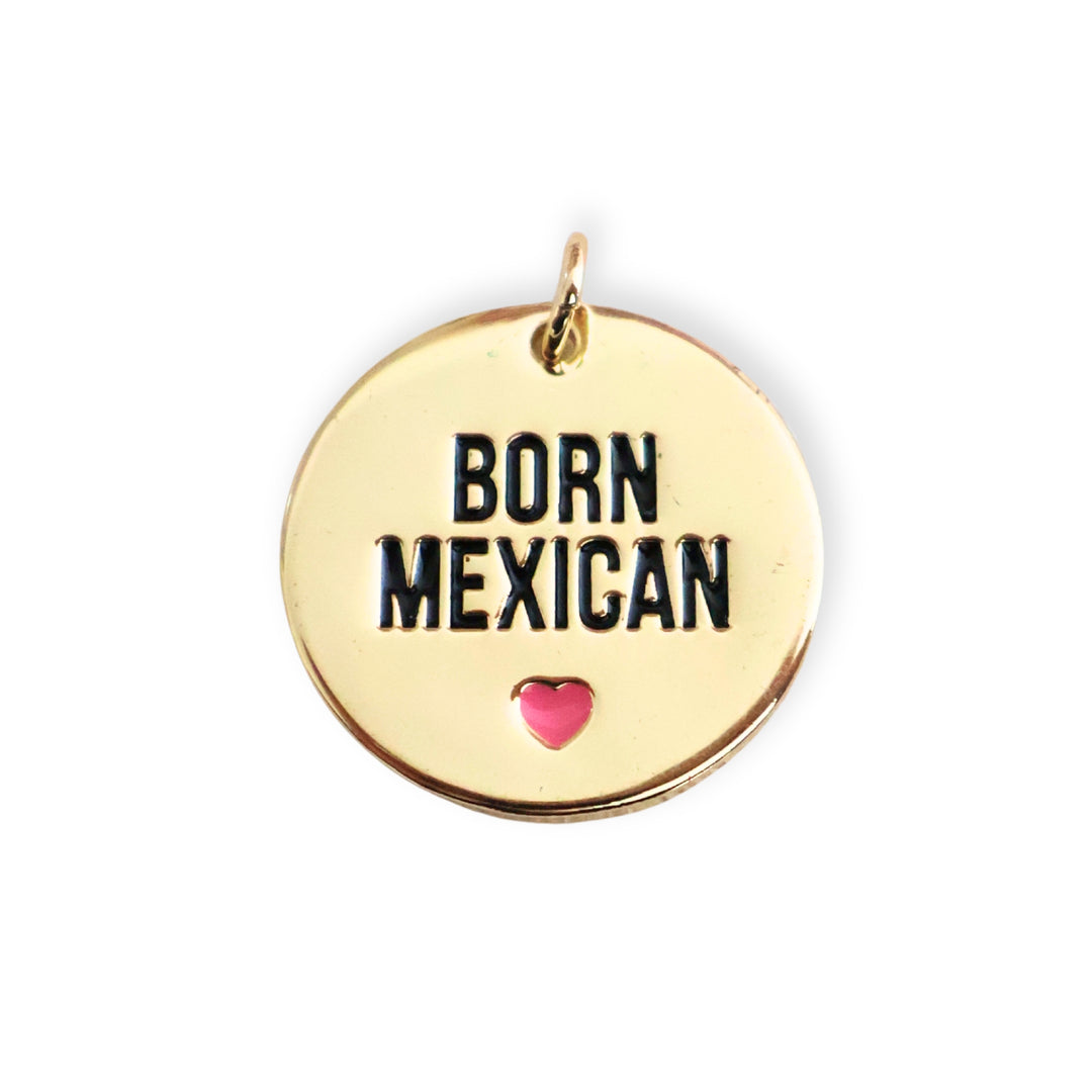 Dije redondo de chapa de oro con frase "BORN MEXICAN" y corazón rosa esmaltado sobre fondo blanco