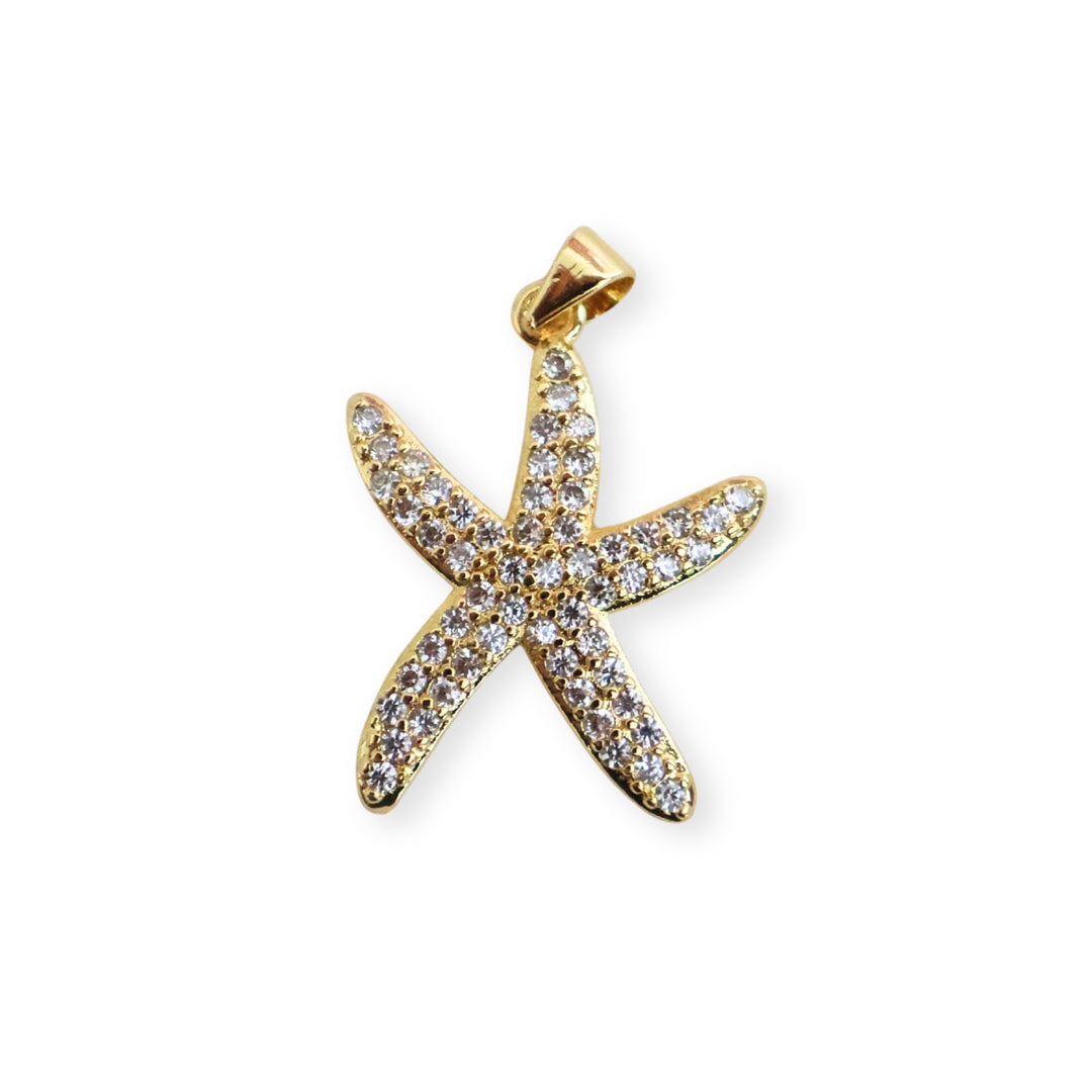 Dije de estrella de mar en chapa de oro con zirconias sobre fondo blanco