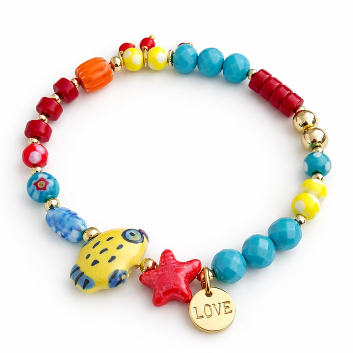 Brazalete marino con pez de cerámica, cristal y dije Love de chapa de oro