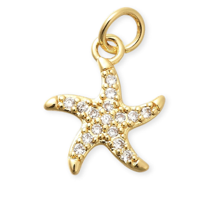 Dije de estrella de mar en chapa de oro con zirconias alrededor sobre fondo blanco
