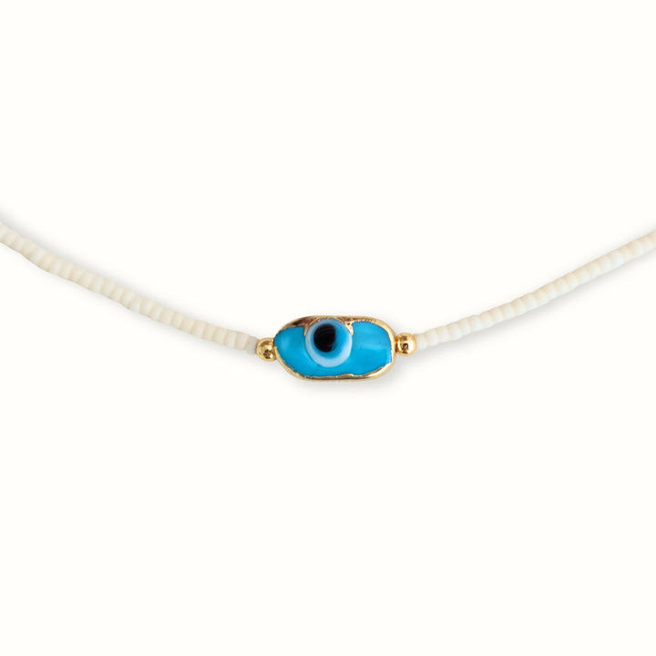 Collar Ophia con chaquira blanca y dije de ojo en chapa de oro