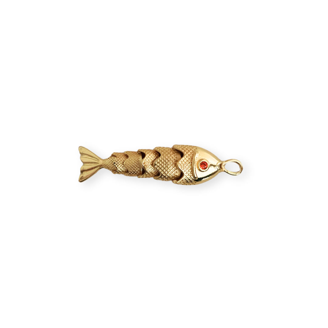 Dije dorado en forma de pescado con zirconia roja en el ojo y cuerpo articulado sobre fondo blanco