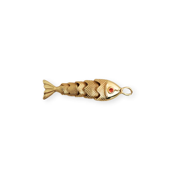 Dije dorado en forma de pescado con zirconia roja en el ojo y cuerpo articulado sobre fondo blanco