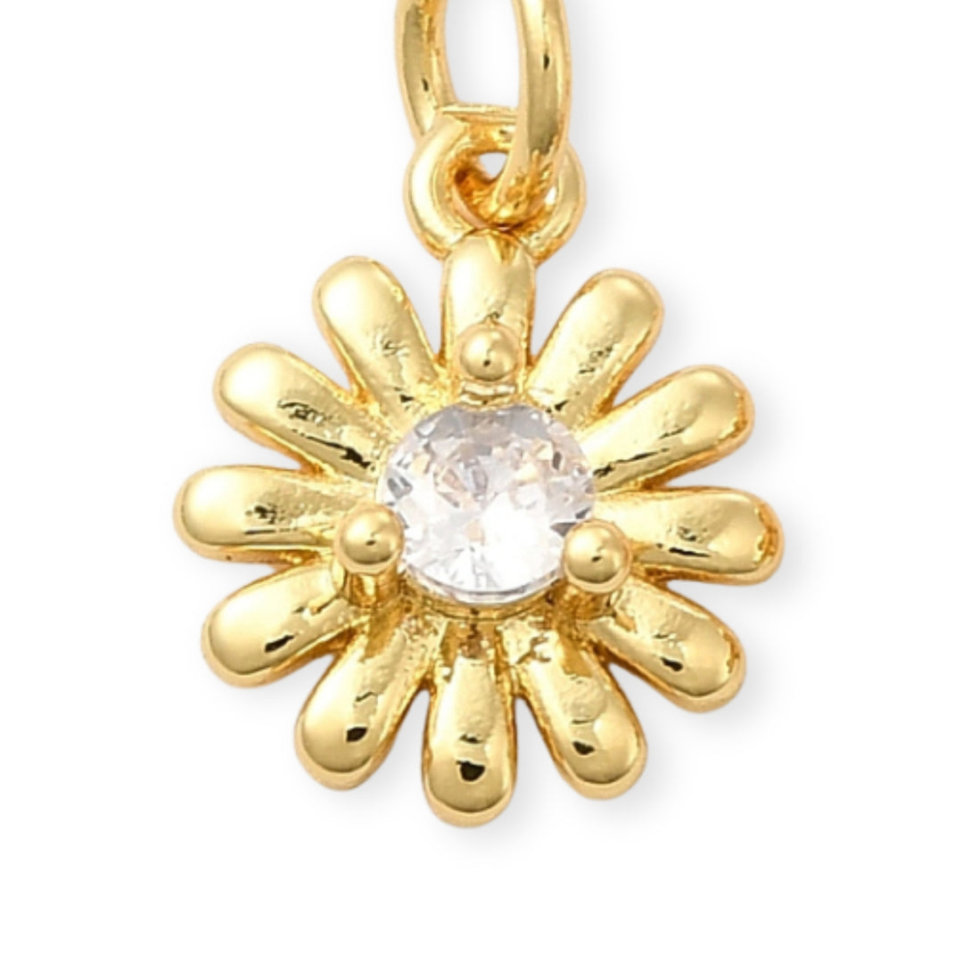 Dije dorado en forma de flor con zirconia brillante al centro