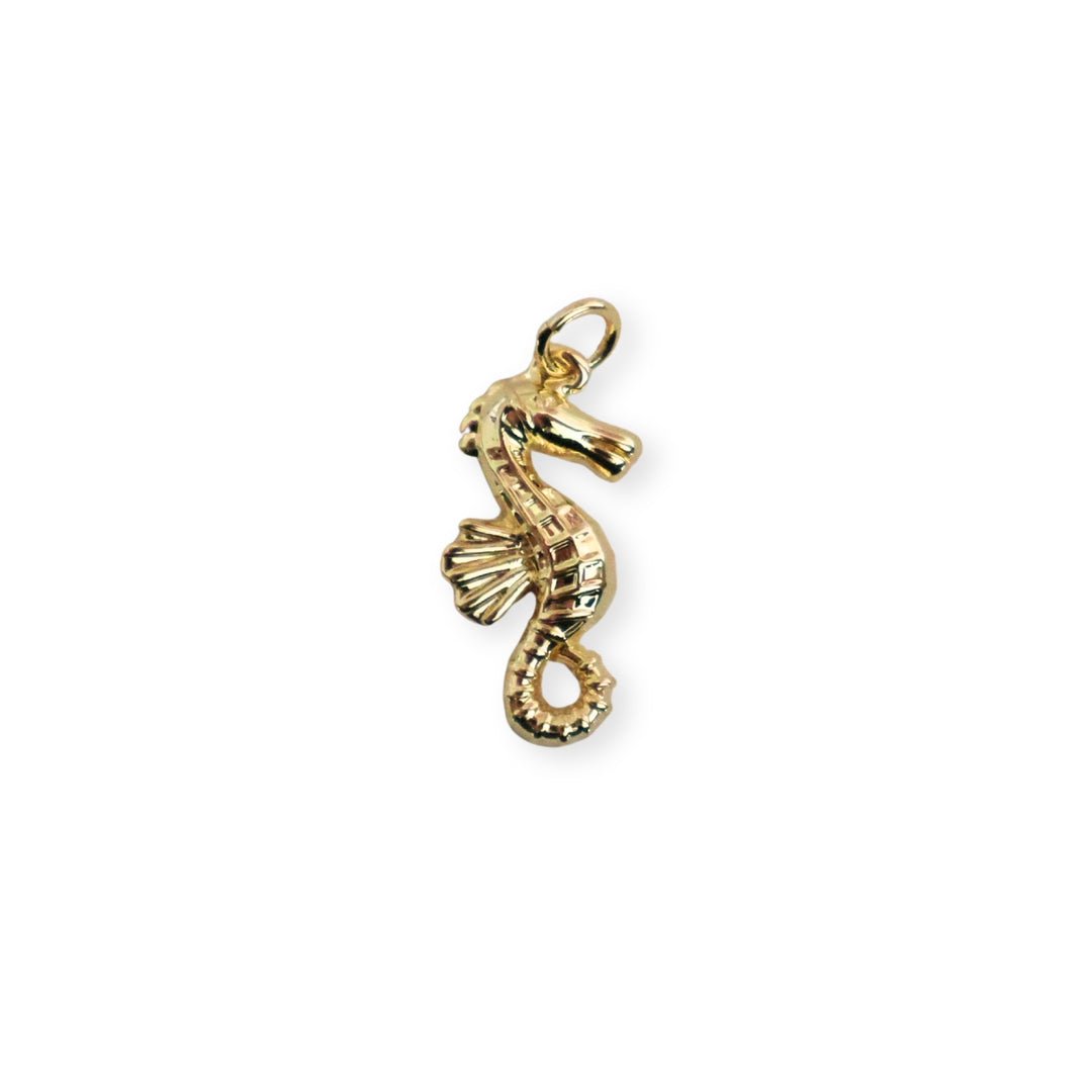 Dije dorado en forma de caballito de mar sobre fondo blanco