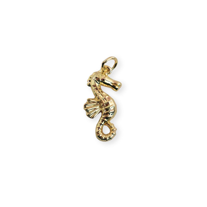Dije dorado en forma de caballito de mar sobre fondo blanco