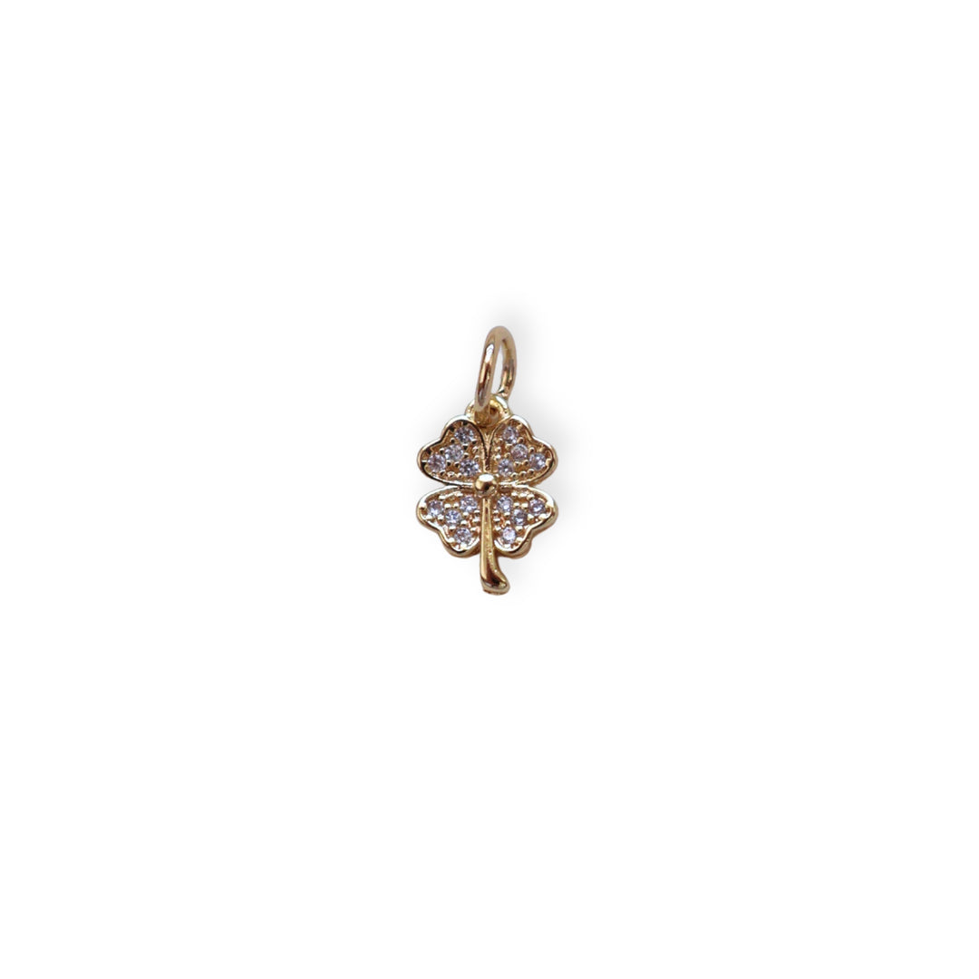 Dije en forma de trébol de chapa de oro con zirconias brillantes sobre fondo blanco