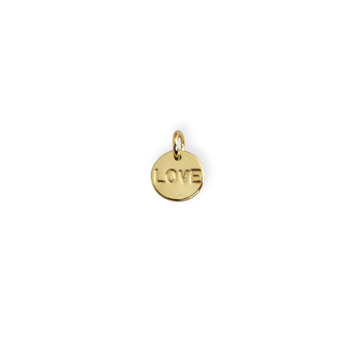 Dije dorado circular con la palabra Love grabada al centro sobre fondo blanco
