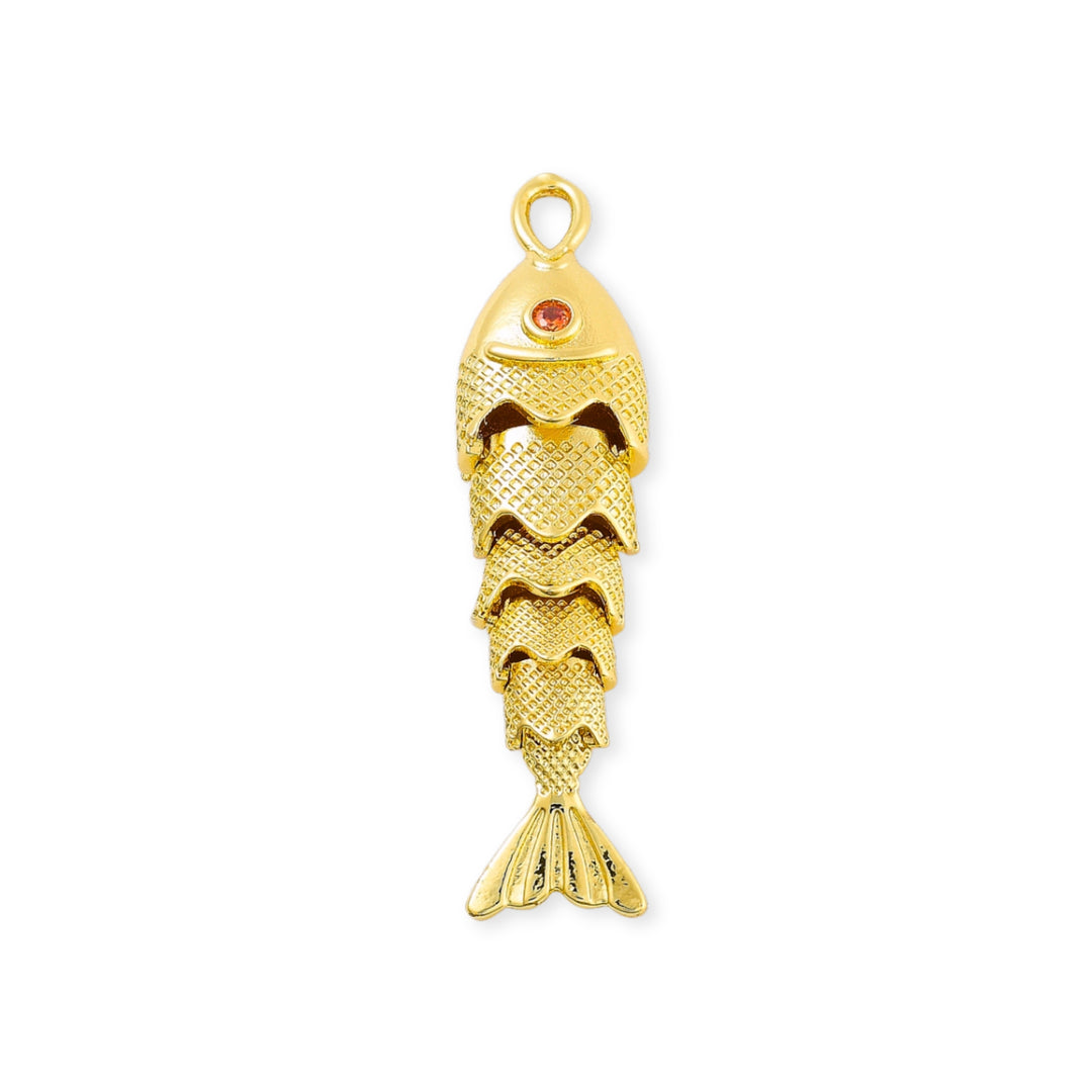 Dije dorado en forma de pescado con zirconia roja en el ojo y cuerpo articulado sobre fondo blanco