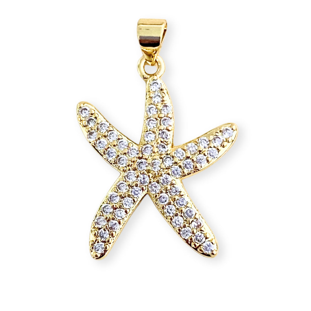 Dije de estrella de mar en chapa de oro con zirconias sobre fondo blanco
