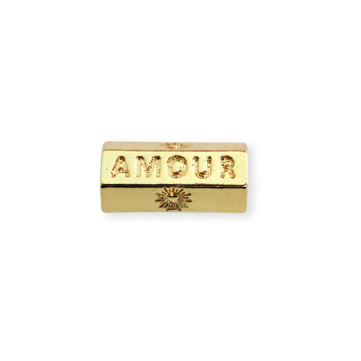 Separador de chapa de oro grabado con la palabra "AMOUR" sobre fondo blanco