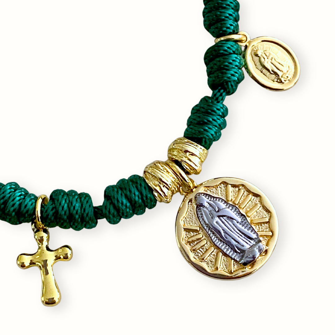 Detalle de Pulsera ajustable con cordón trenzado y dijes religiosos de Virgen María y cruz en chapa de oro. 