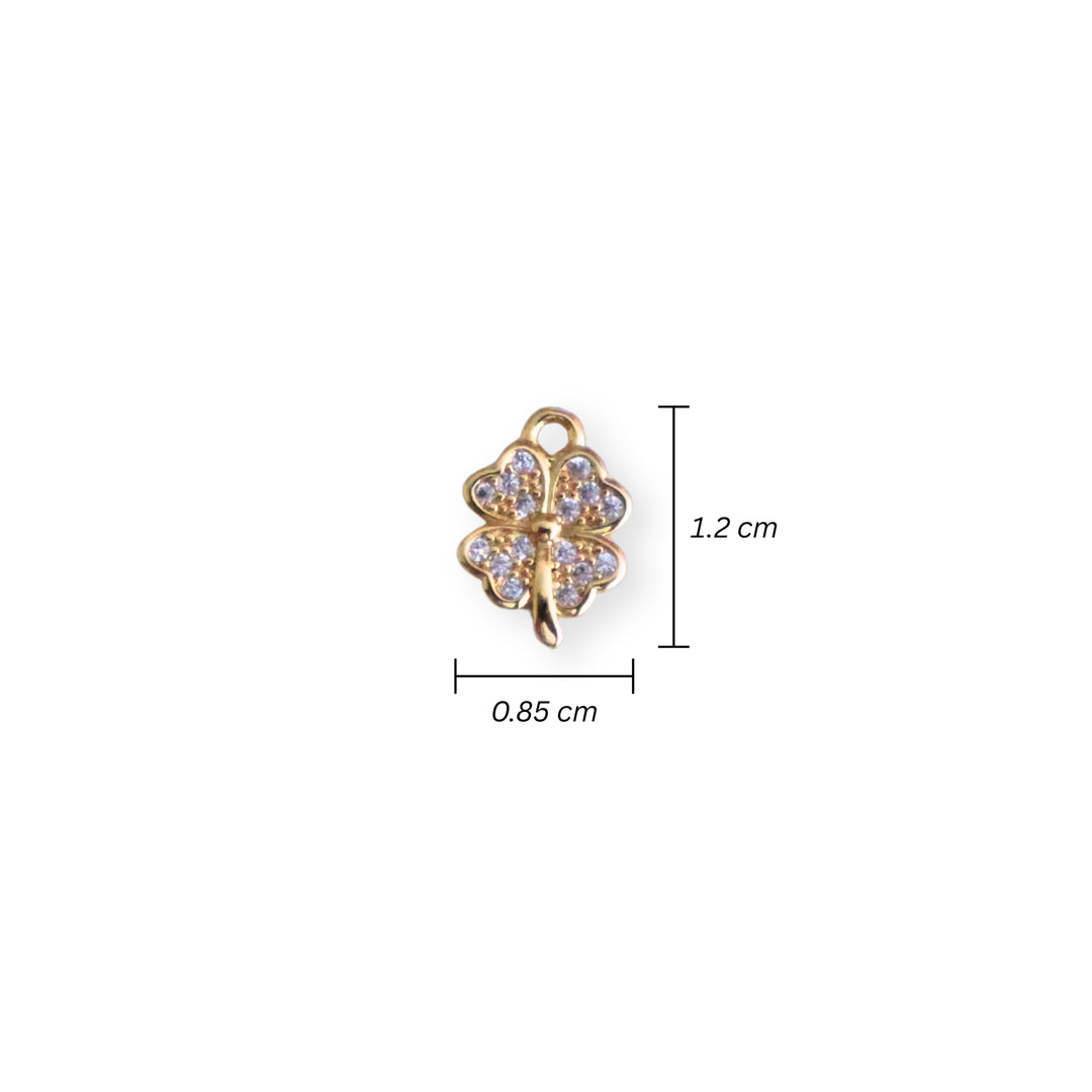 Medidas para dije dorado en forma de trébol con zirconia al centro sobre fondo claro