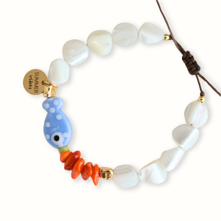 Detalle de Pulsera Mileia tejida en hilo café con madreperla y pez azul