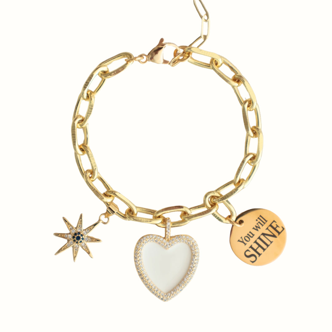 Detalle de dijes con zirconia y placa "You will SHINE" en la pulsera Aureva