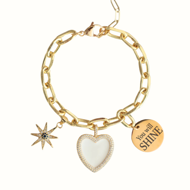 Detalle de dijes con zirconia y placa "You will SHINE" en la pulsera Aureva