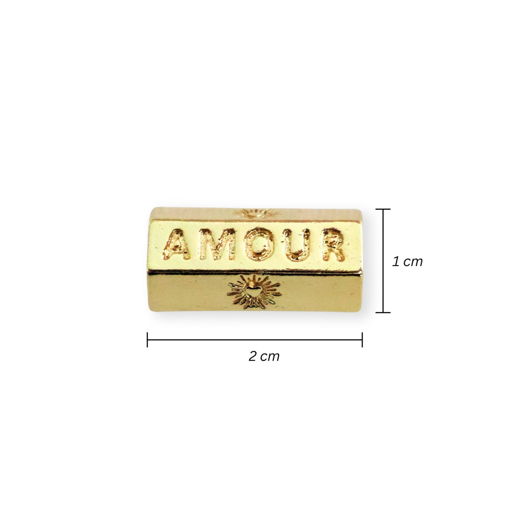 Detalle de medidas para separador de chapa de oro grabado con la palabra "AMOUR" sobre fondo blanco