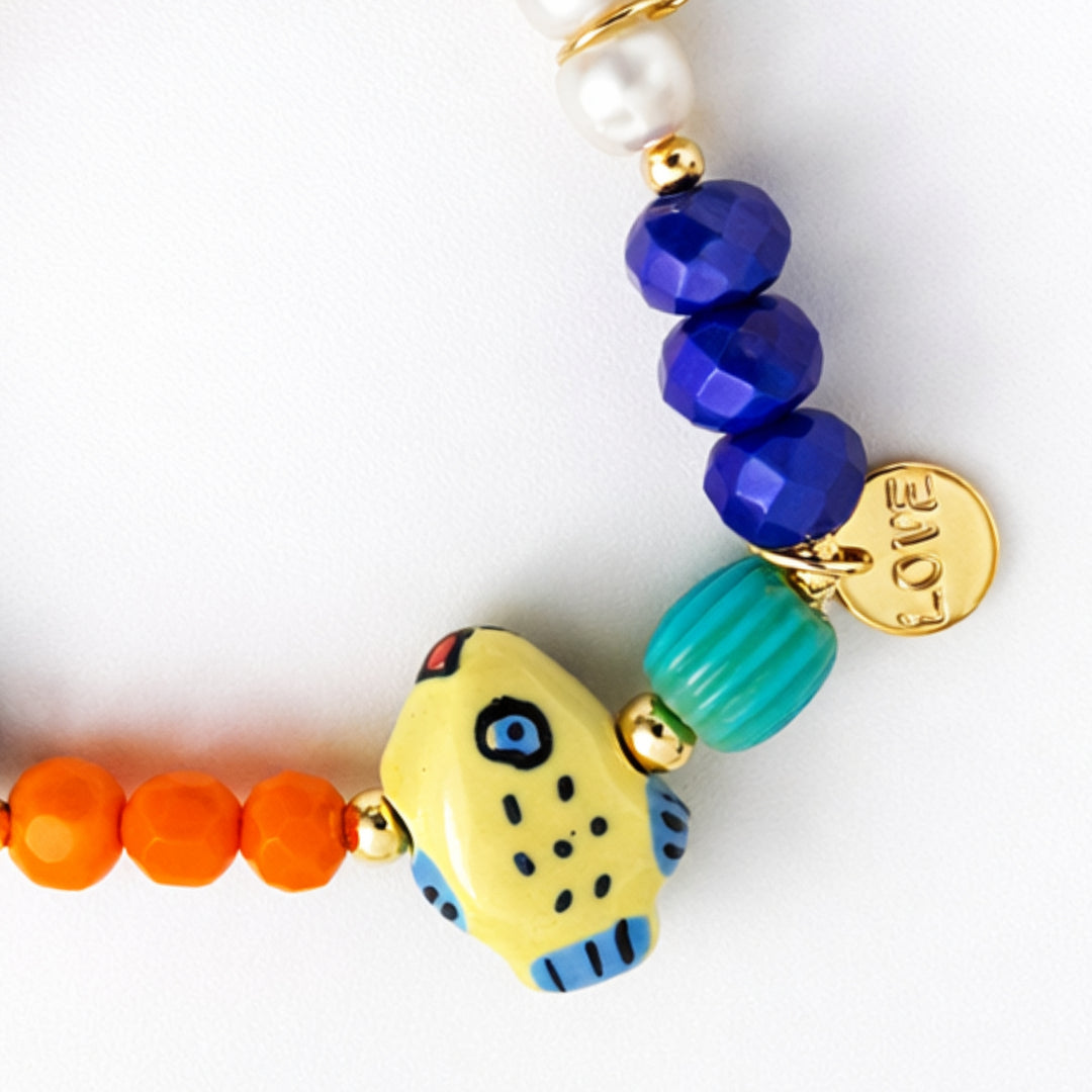 Detalles de Brazalete marino con pez de cerámica, perla cultivada y dije Love de chapa de oro