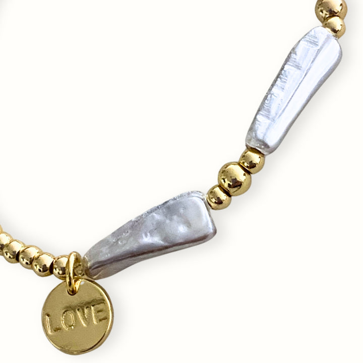 Detalles de Pulsera elástica con madre perla nacarada y dije Love de chapa de oro. 