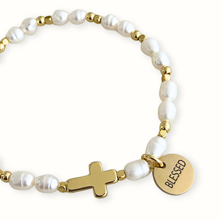 Pulsera elástica con perla de río, cruz y dije Blessed.