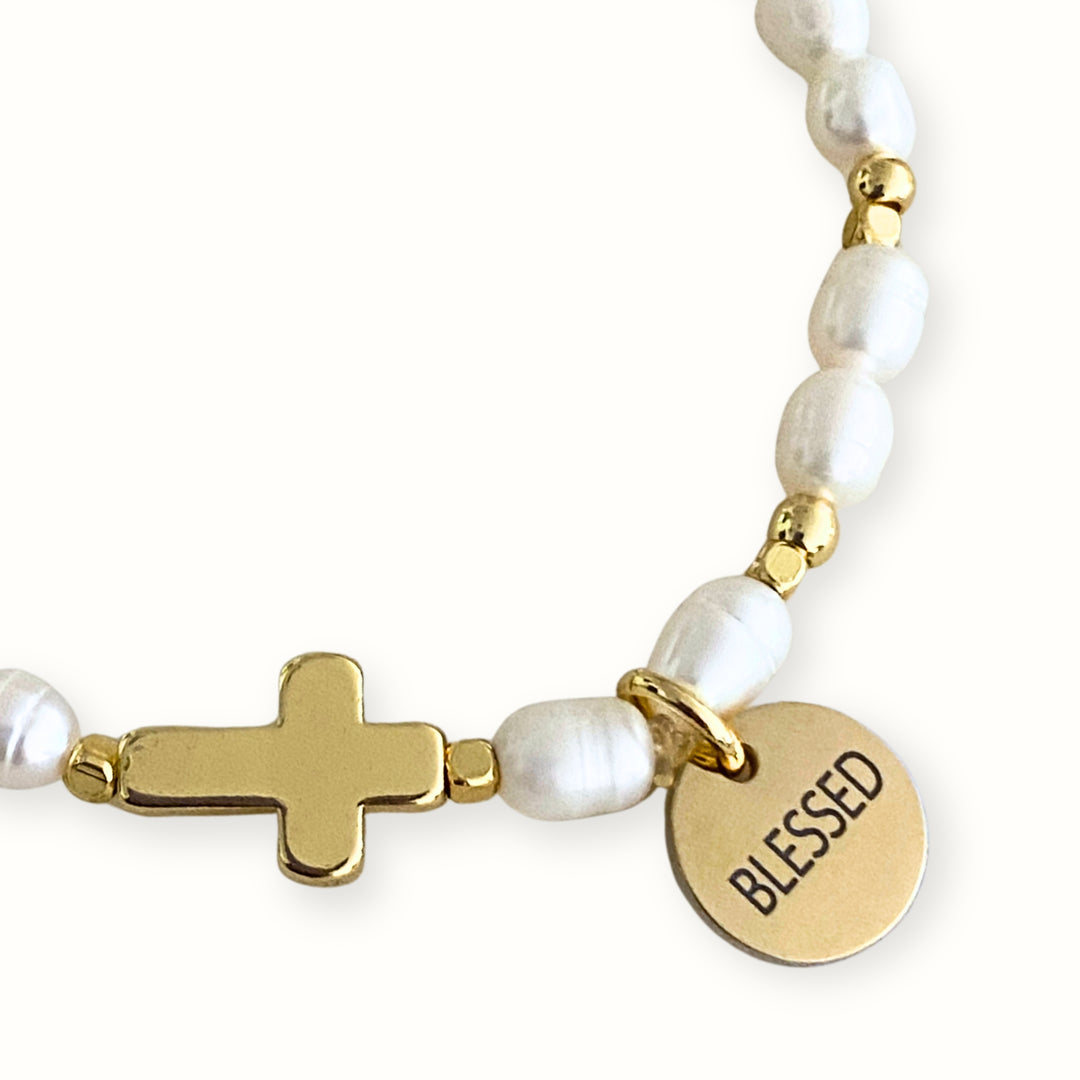 Detalles de Pulsera elástica con perla de río, cruz y dije Blessed.