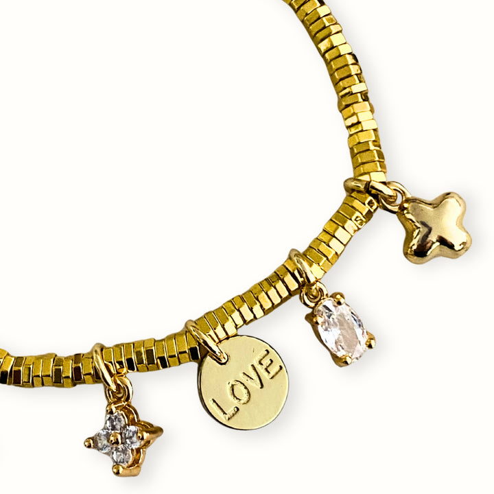 Detalles de Pulsera ajustable con hilo chino, hematita dorada y dijes de flor, cruz y Love en chapa de oro con zirconia.
