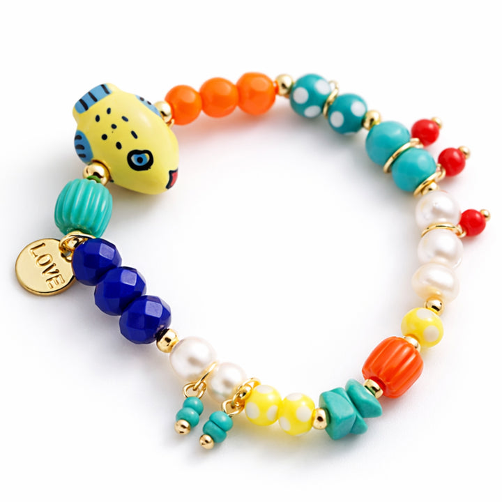 Detalles de Brazalete marino con pez de cerámica, perla cultivada y dije Love de chapa de oro