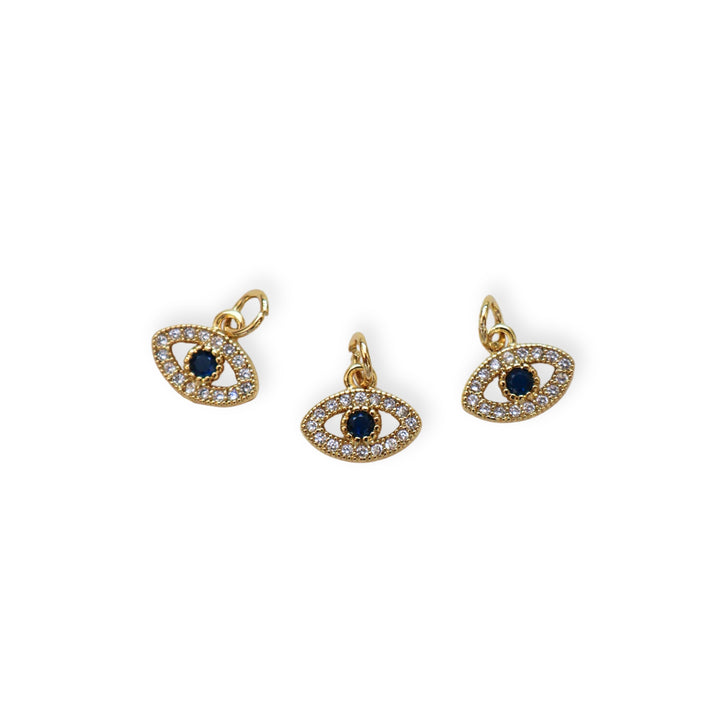 Detalles de dije dorado en forma de ojo con zirconias y centro azul oscuro