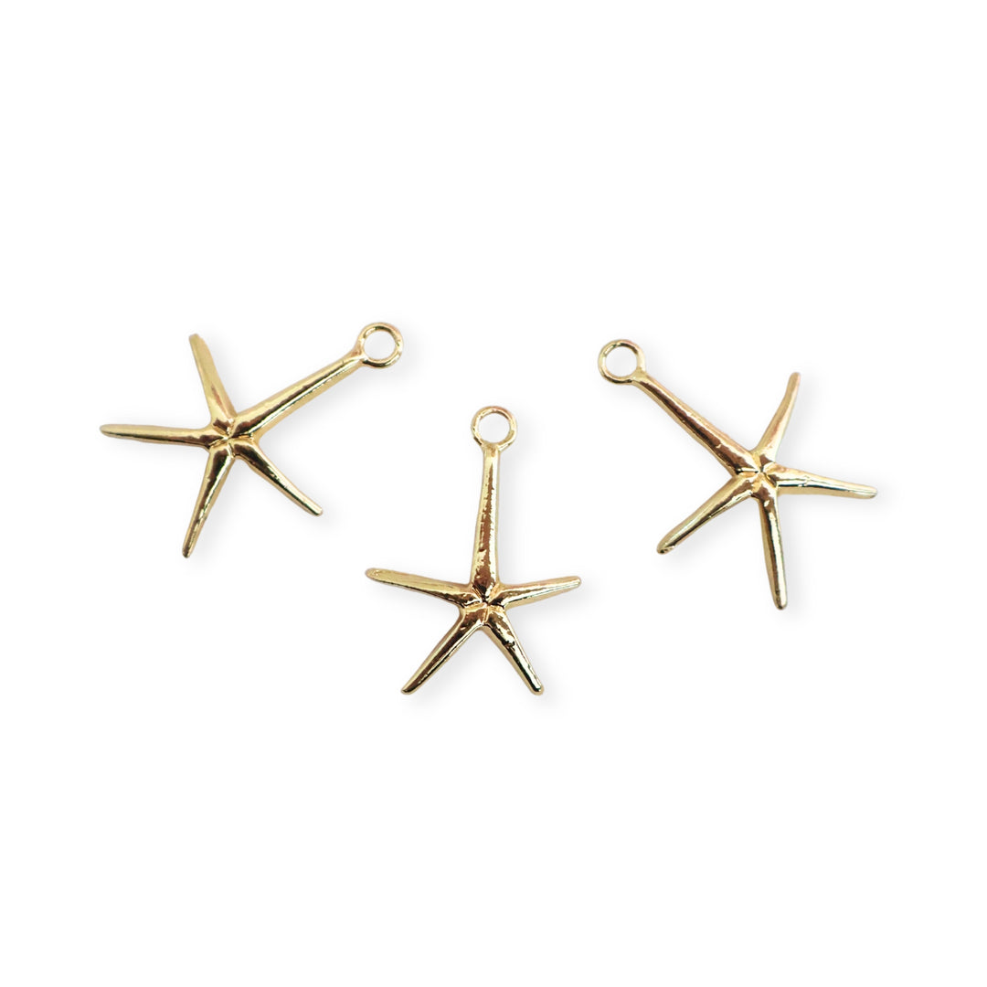 Detalle de dijes de estrella de mar dorada en fondo blanco