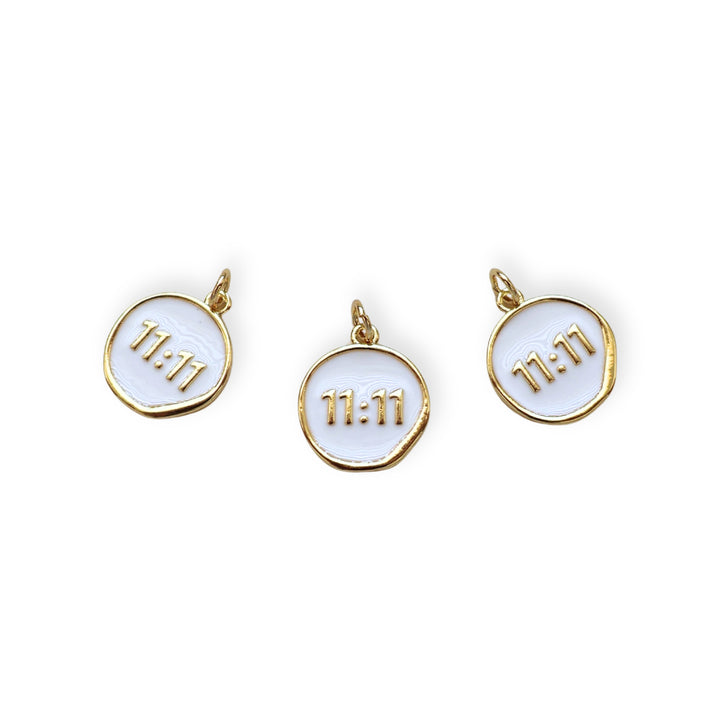 Detalles de dije circular dorado con “11:11” esmaltado en blanco