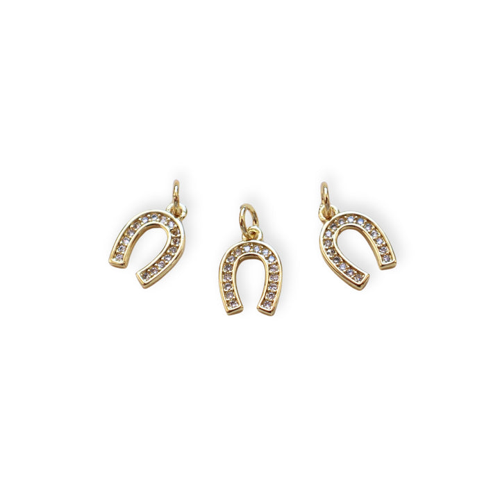 Detalles de dije dorado en forma de herradura de caballo con zirconias