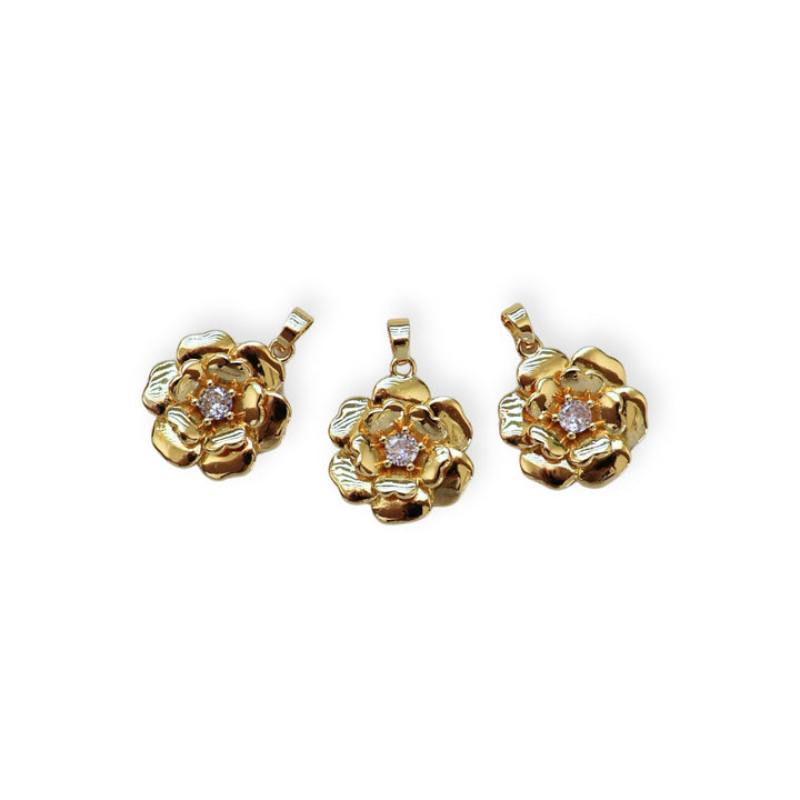 Detalles de dije dorado en forma de flor con zirconia al centro