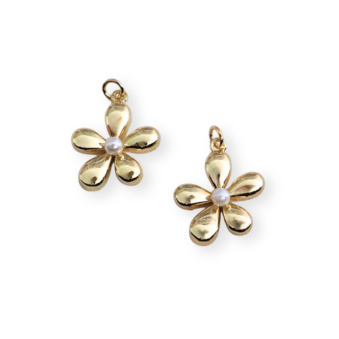 Detalles de dije de flor en chapa de oro con perla sintética al centro, diseño elegante y delicado.