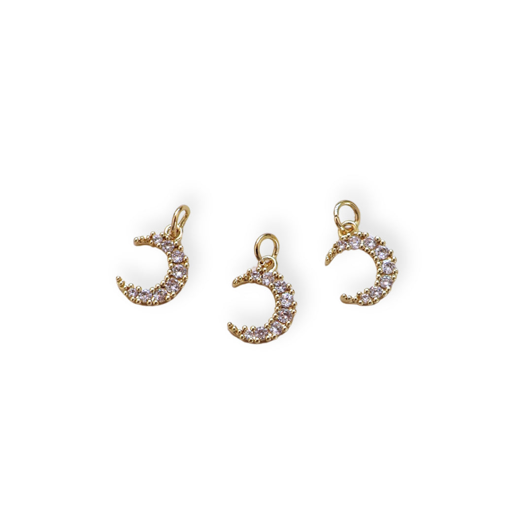 Detalles de dije dorado en forma de luna con zirconia