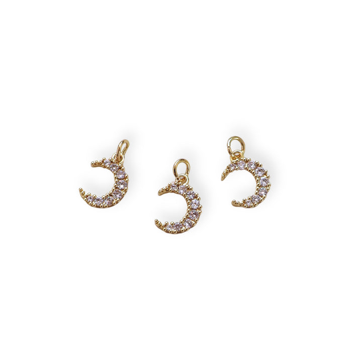 Detalles de dije dorado en forma de luna con zirconia