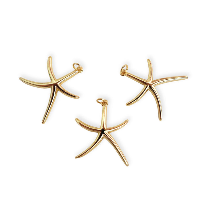 Detalles de dijes en forma de estrella de mar elaborado en chapa de oro sobre fondo blanco