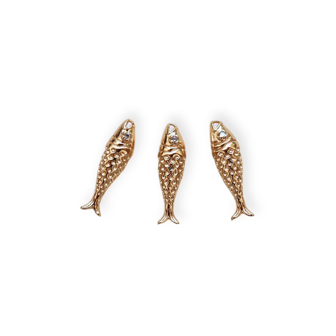 Detalles de dije en forma de pez dorado en chapa de oro con zirconia en el ojo