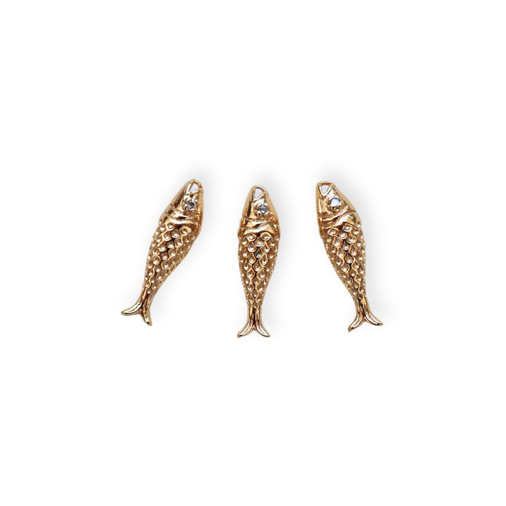 Detalles de dije en forma de pez dorado en chapa de oro con zirconia en el ojo