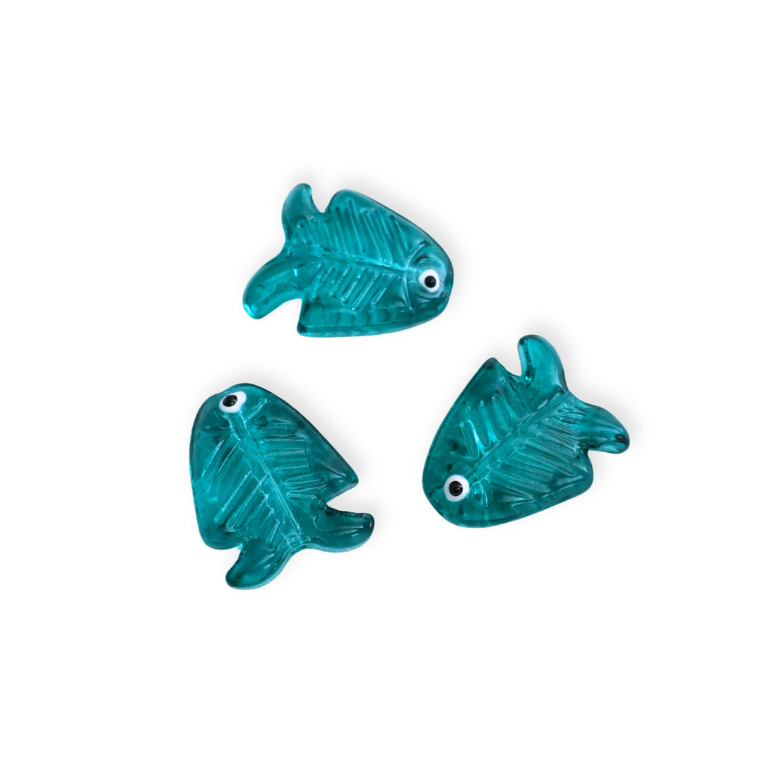 Detalle de conectores de vidrio en forma de pescado color teal sobre fondo blanco


