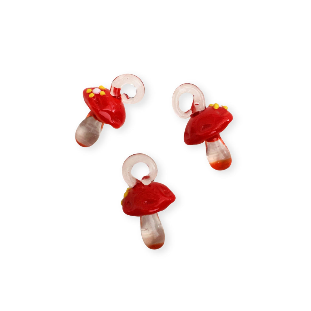 Detalles de dijes de murano en forma de hongo con sombrero rojo y cuerpo transparente