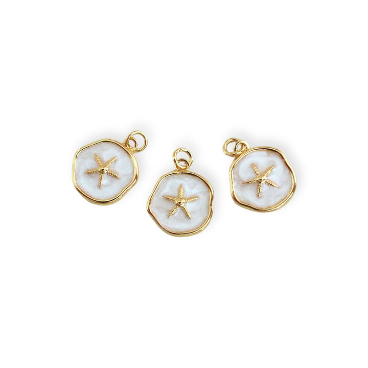 Detalles de dijes circulares blancos con estrella de mar dorada al centro