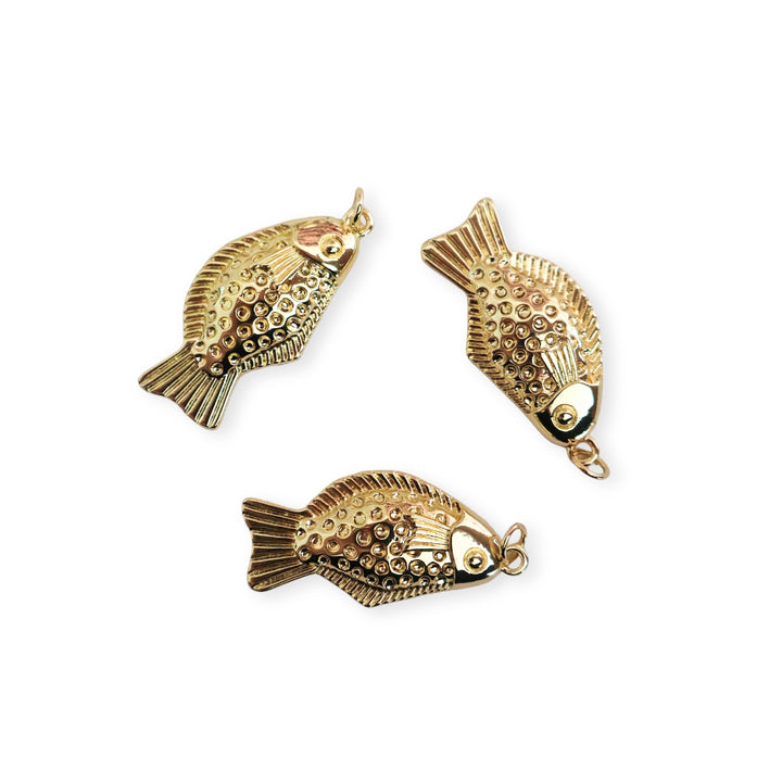 Detalles de dijes de pescado en chapa de oro con acabado brillante sobre fondo blanco