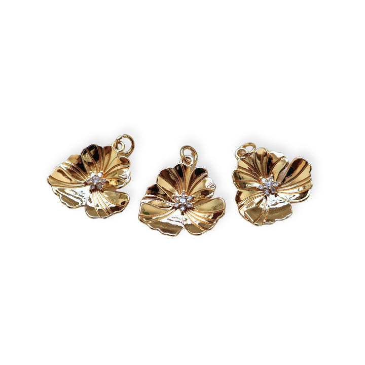Detalles de dije flor dorada en chapa de oro con zirconia en el centro