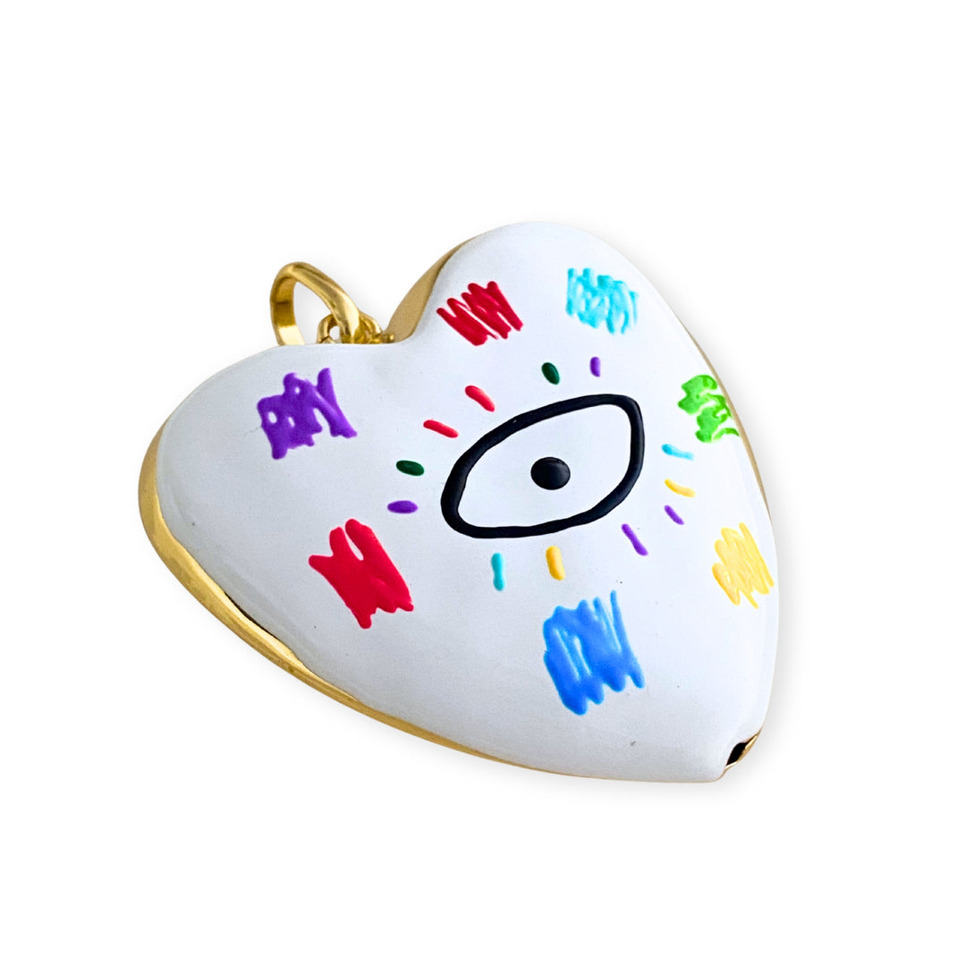 Detalles de Dije grande de corazón esmaltado blanco con ojo central y detalles multicolor en chapa de oro. 
